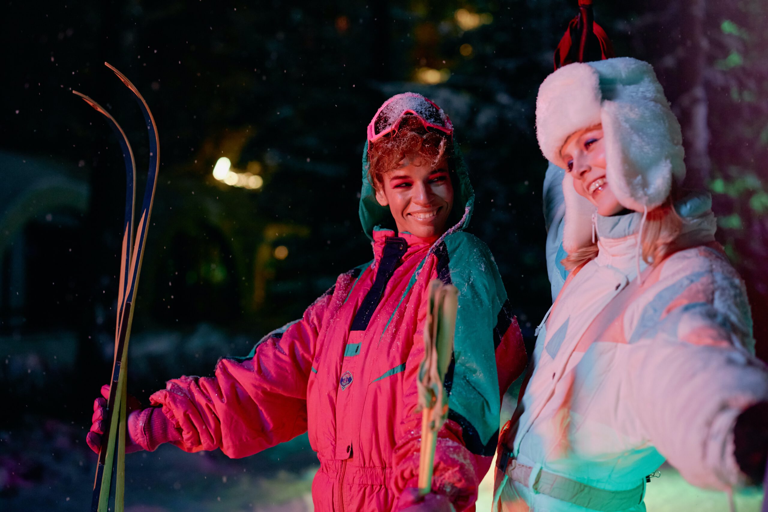 Dwie kobiety ubrane w kolorowe kombinezony narciarskie w stylu lat 80.